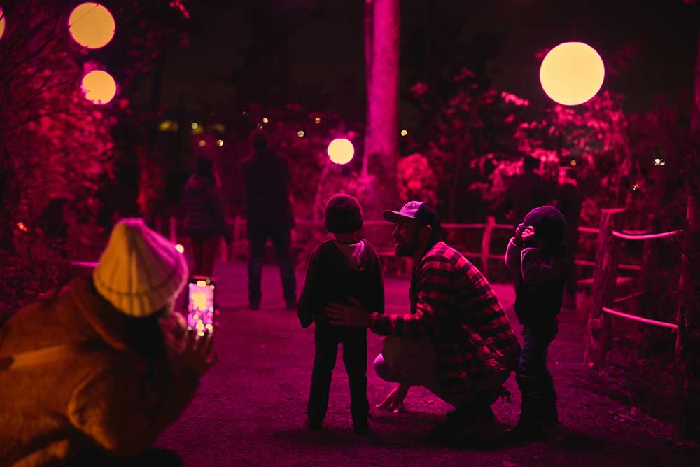 A group of individuals stands in a dimly lit space illuminated by vibrant pink lights.